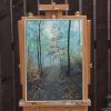 Misty Woodland on an easel: a path through tall trees in the mist.