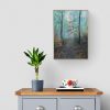 Misty Woodland hanging above a grey sideboard with a plant.