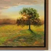 Detail of Radiant: the sun behind a tree in the field, with the signature in orange.