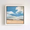 A wide beach under a blue sky with tall white clouds, shallow water running across pale sand.
