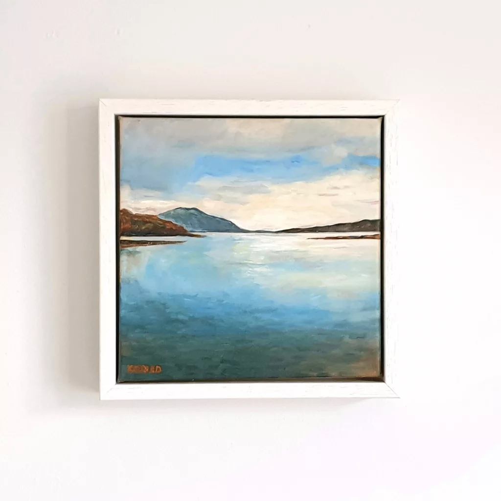 A still loch reflecting a pale sky between low hills.