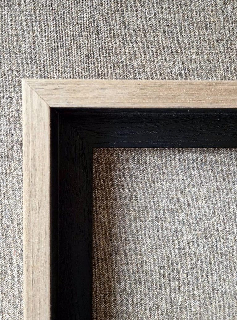 Corner of a natural wood picture moulding with a black inner edge